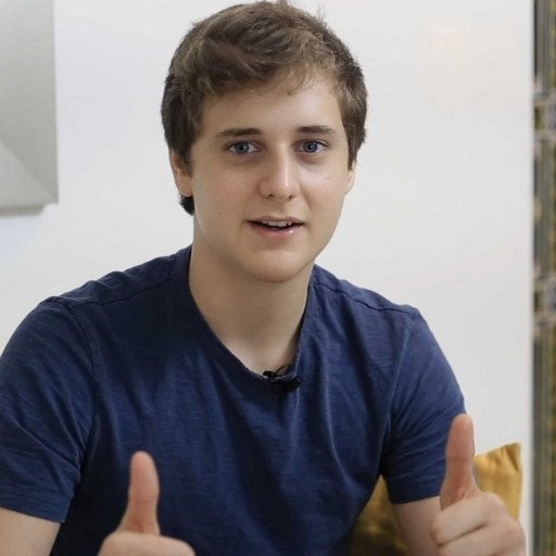 A young man giving thumbs up on a couch.