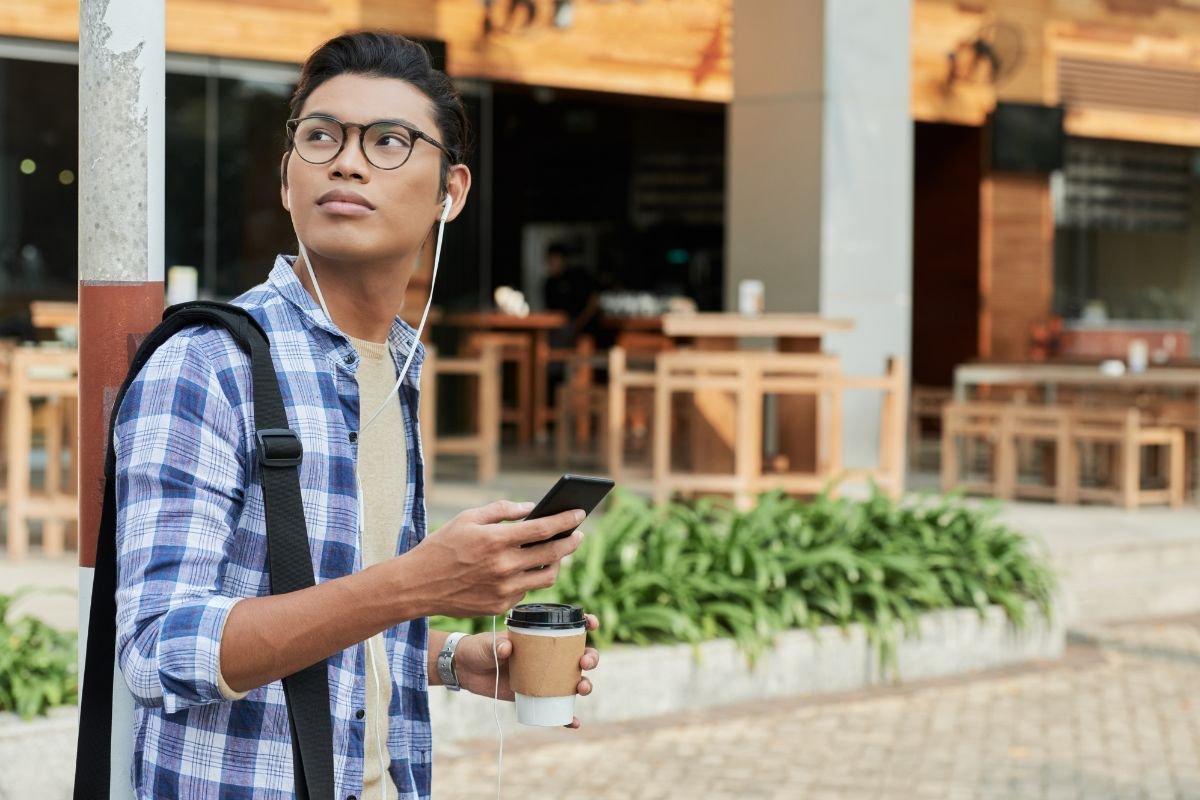 boy touring the university during his first day of classes while having a coffee and listening to music