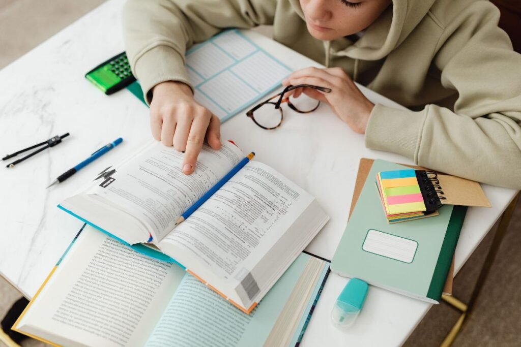 Woman studying with various books around.
