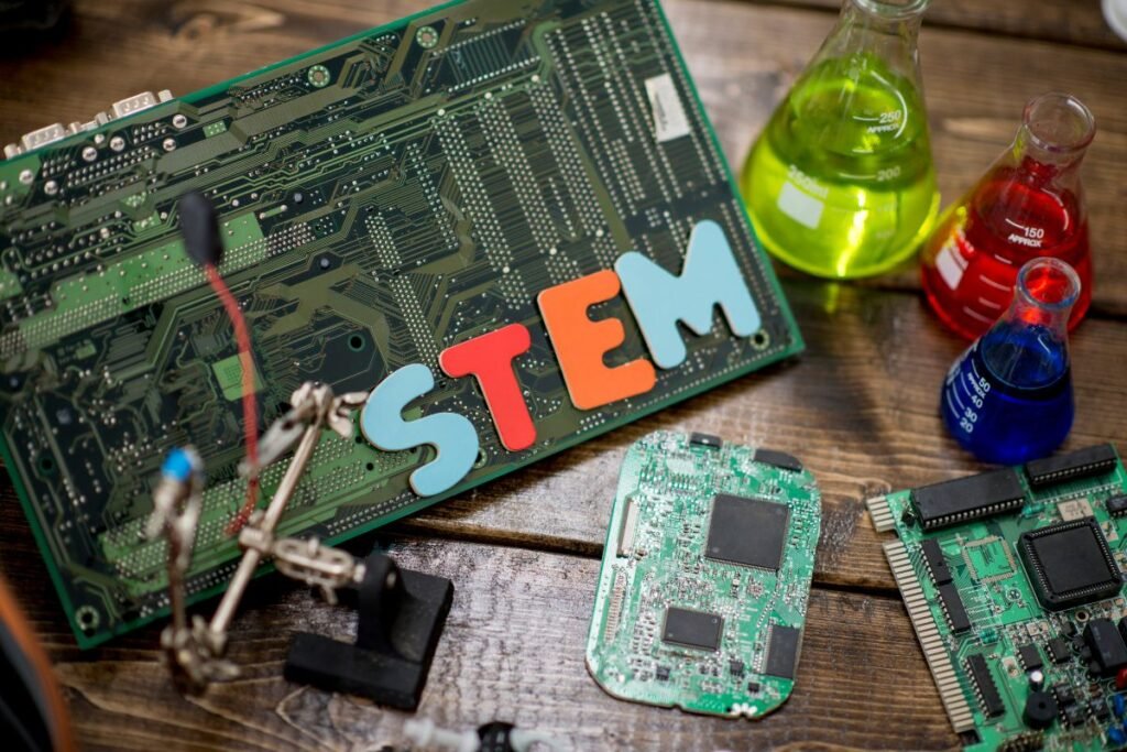 Stem concept with circuit boards and colorful laboratory flasks on a wooden surface.