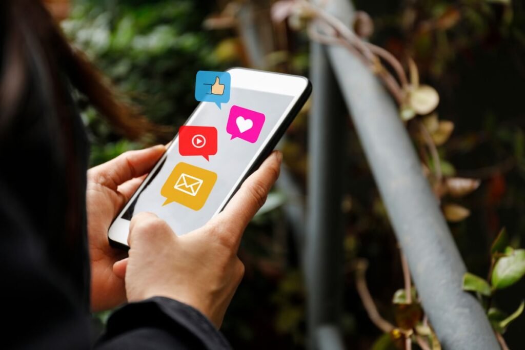 A woman holding a smart phone with social icons on it.