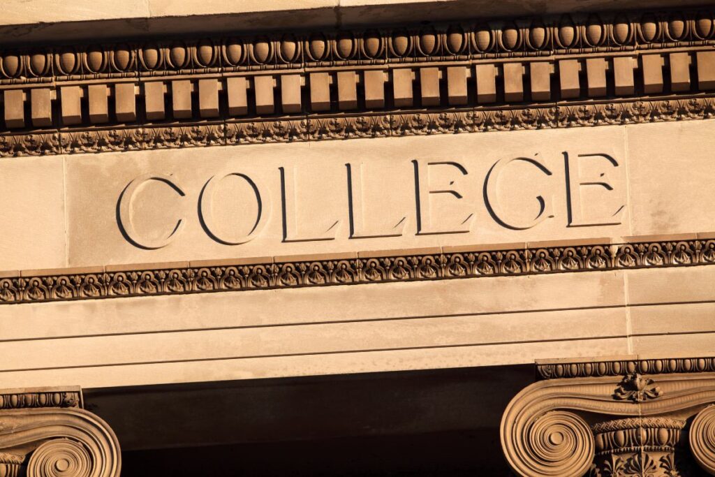 Close-up of ornate stone architecture with the word "COLLEGE" engraved on the facade.